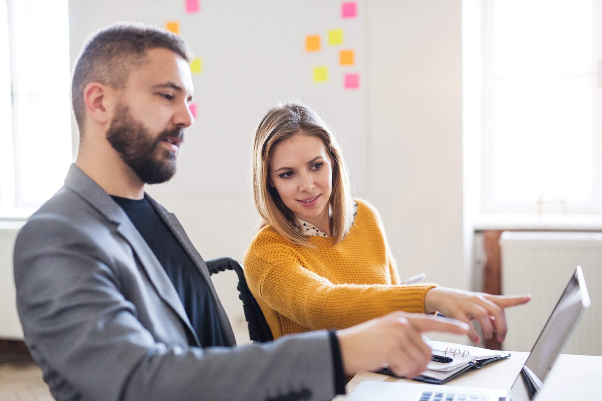 Two business people with wheelchair in the office.