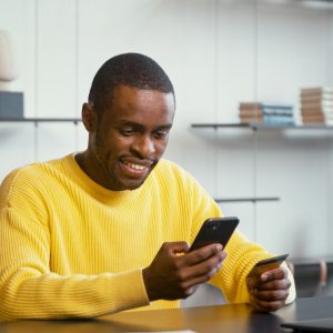 Smiling financial director in yellow shirt looks at bank card in hand