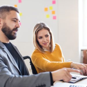 Two business people with wheelchair in the office.
