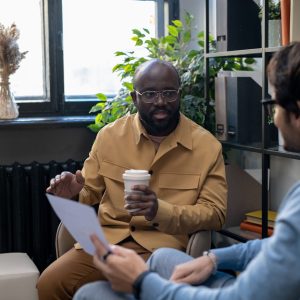 Young African-American man consulting his colleague with paper